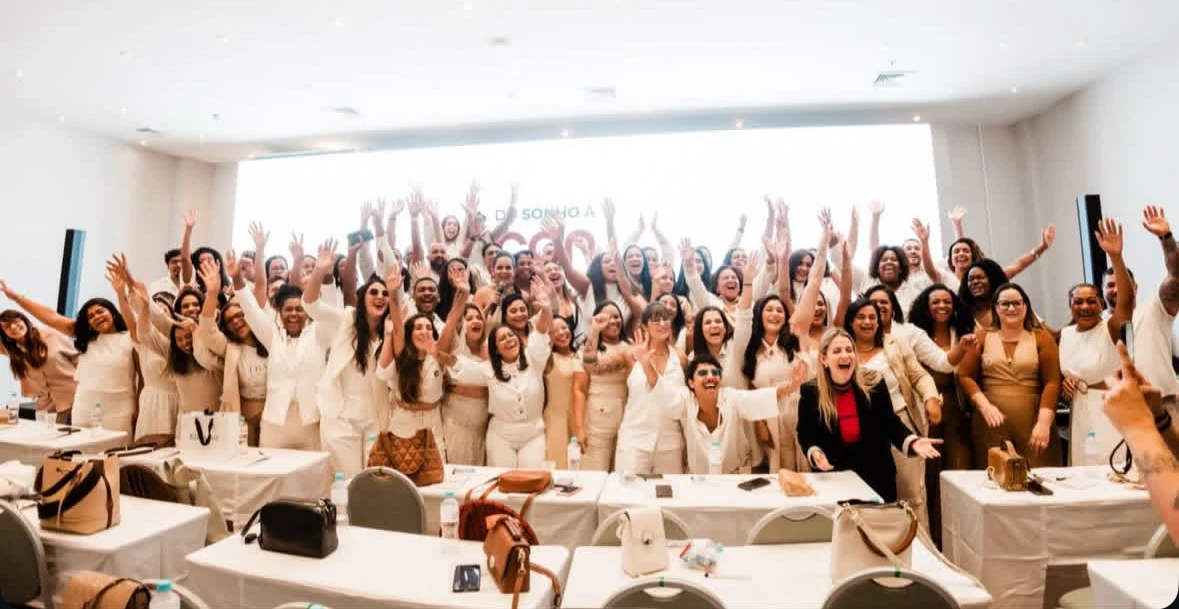 Paula Angelini comemorando com uma turma de mulheres, todas de braços erguidos
